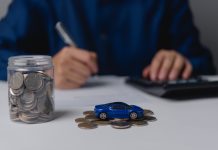 Autofinanzierung leicht gemacht: Exklusive Vorteile für ARCD-Mitglieder bei der PSD Bank West Auf einem Tisch steht ein Einmachglas gefüllt mit Geldmünzen, daneben ein kleines blaues Spielzeugauto auf ein paar weiteren Münzen