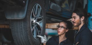 So sparen Sie clever: Exklusive Werkstattvorteile bei DRIVER für ARCD-Mitglieder Ein weiblicher und ein männlicher Automechaniker prüfen den Reifen an einem aufgebockten Fahrzeug