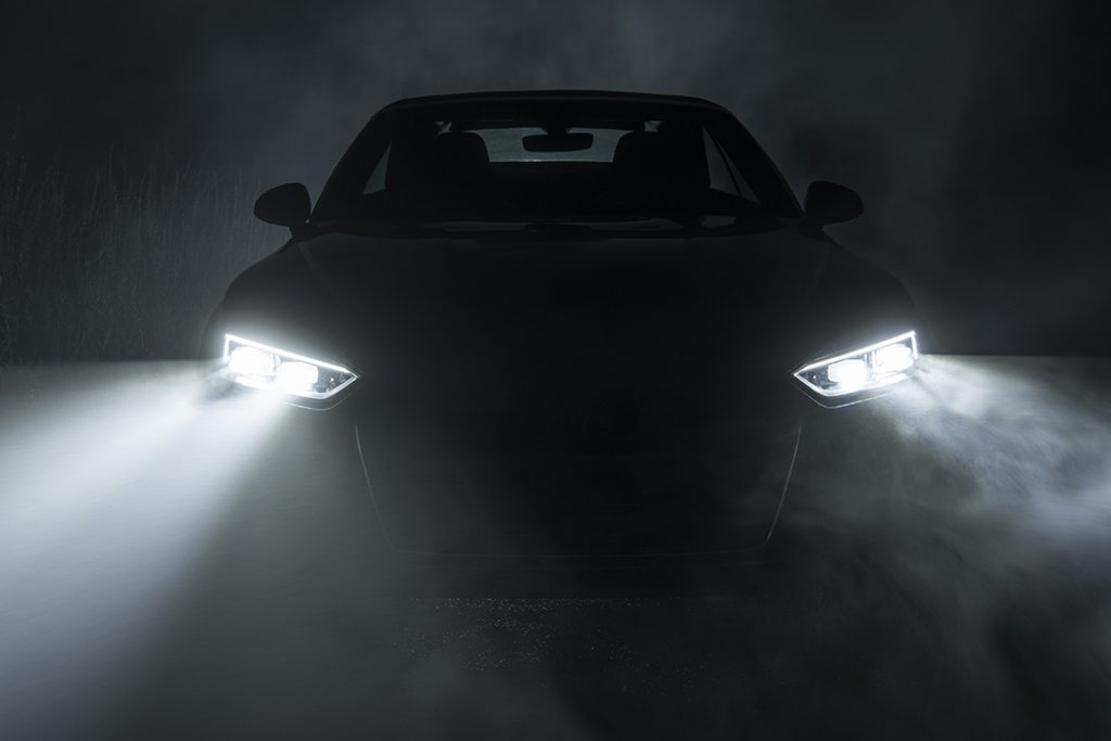 Ein Auto in dunkler Nacht von vorn im Nebel mit eingeschalteten LEDSCheinwerfern